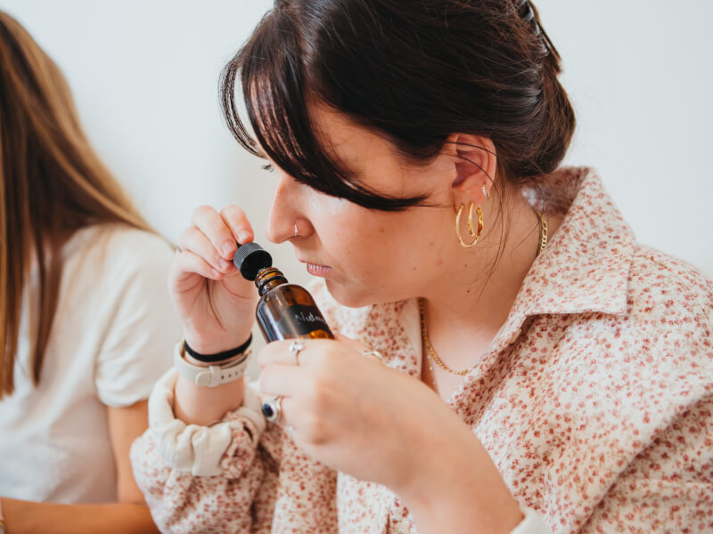 Woman holding a dropper bottle and smelling contents